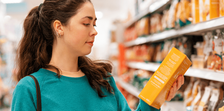 Woman holding a box in a grocery store, highlighting a visual merchandising strategy to enhance product visibility and appeal